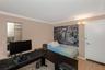 Room featuring wood-finish flooring, crown molding, dual-panel closet doors with mirror inserts, and wall-mounted light fixture
