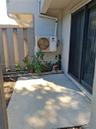 Concrete patio, sliding glass door with a metal frame, and wood-slat privacy fencing