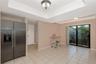 Tray ceiling with crown molding, stainless steel side-by-side refrigerator, ceramic tile flooring, and sliding glass doors
