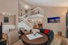 Vaulted ceiling, open mezzanine with white balustrade, wood-finish flooring, and built-in cabinetry