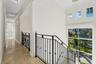 Neutral stone flooring, matte black wrought iron railings with decorative scrollwork, high ceilings, recessed lighting, and large windows featuring mu
