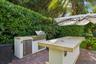 Outdoor kitchen featuring a built-in stainless steel grill, stone-finish countertop, integrated under-counter refrigeration, and paver patio flooring