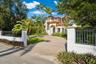 Mediterranean-style residence featuring a tile roof, stucco exterior, gated entrance with masonry pillars, and a paver driveway