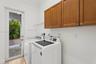 Laundry area featuring wood-finish cabinetry, stone flooring, and a glass-paneled exterior door
