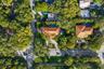 Aerial perspective of a property featuring a tiled roof, circular driveway, swimming pool, and dense perimeter landscaping
