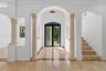 Grand foyer featuring stone columns, arched entryways, stone tile flooring with decorative inlay, and a multi-lite glass double door