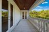 Covered balcony featuring a natural wood-finish plank ceiling, stone tile flooring, and a decorative stone balustrade with French door access