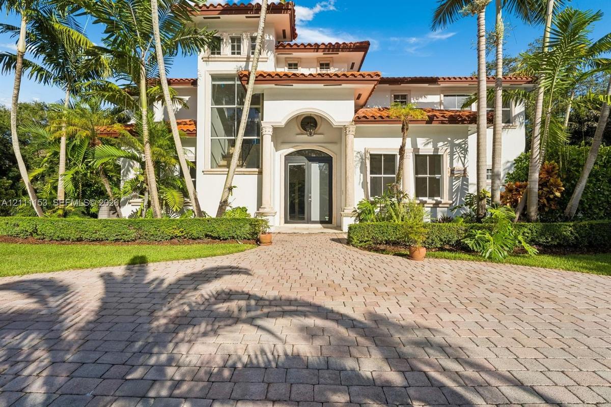 Mediterranean-inspired exterior featuring a clay tile roof, arched entryway with classical columns, stucco facade, multi-story glass window panel, and
