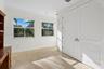 Room featuring stone flooring, dual-panel white doors, crown molding, and two windows