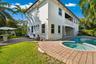 Stucco exterior residence featuring an integrated pool and spa, brick paver patio, second-story balcony, and manicured grounds