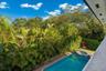 Backyard featuring a swimming pool, integrated spa, brick paver decking, and mature tropical landscaping