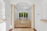 Entryway featuring arched architectural details, decorative stone columns, polished stone flooring with inlaid border, recessed lighting, and glass pa