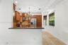Kitchen featuring raised-panel wood cabinetry, stone countertops, stainless steel appliances, a decorative crystal chandelier, and natural stone floor