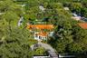 Residential property featuring a clay tile roof, arched entryway, paved circular driveway, and mature landscaping