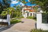 Mediterranean-style residence featuring a terra cotta tile roof, arched entryway with decorative columns, paved driveway, stucco exterior, and gated p
