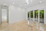 Neutral-toned stone tile flooring, multi-panel sliding glass doors, recessed lighting, and a multi-bulb modern ceiling light fixture