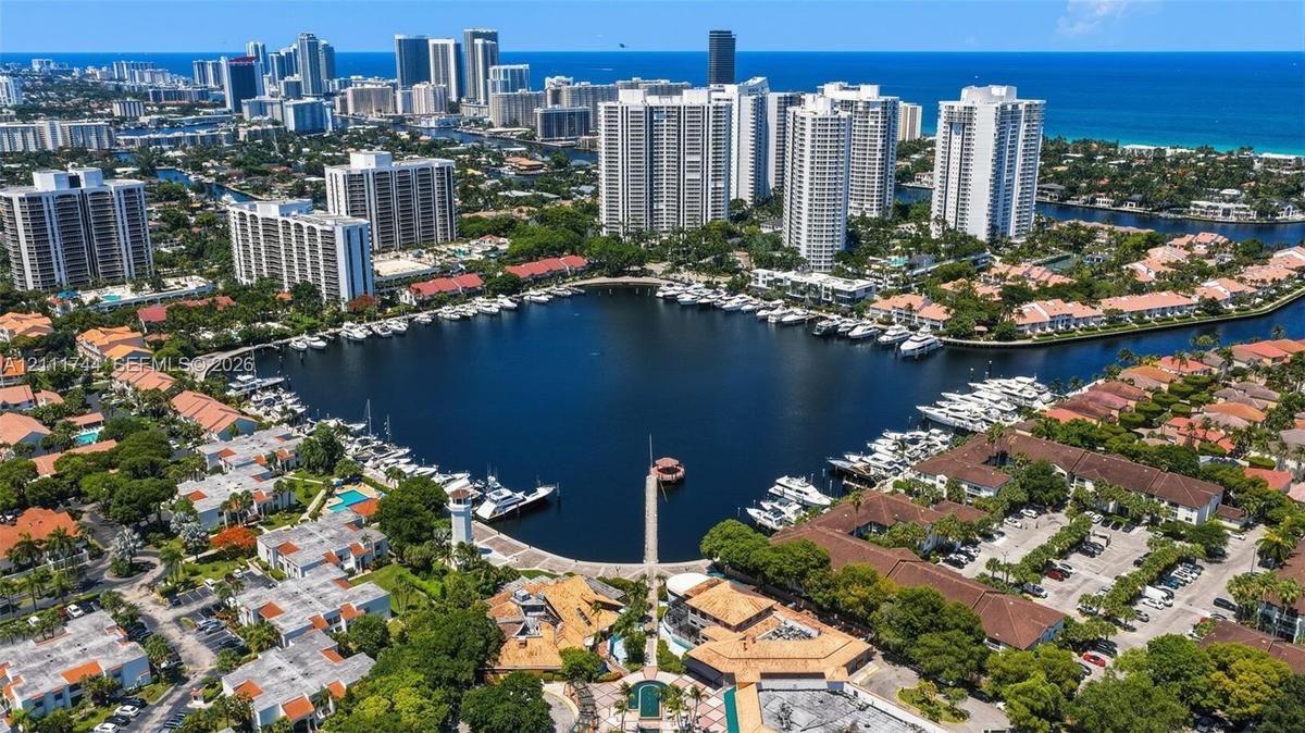 Aerial perspective featuring a deep-water marina, boat slips, coastal waterway access, and urban skyline backdrop