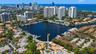 Aerial perspective featuring a deep-water marina, boat slips, coastal waterway access, and urban skyline backdrop