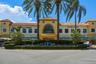 Mediterranean-inspired commercial exterior featuring a tile roof, decorative arched stonework above the central balcony, a blue-tiled water feature, a