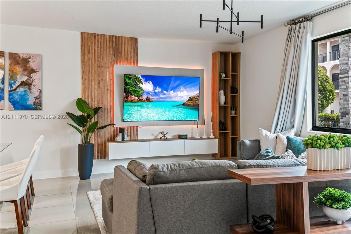 Living space featuring vertical wood slat wall detailing, a wall-mounted entertainment console, integrated accent lighting, built-in shelving, and a m