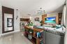Open-concept interior featuring large-format tile flooring, vertical wood-slat wall accents, contemporary multi-arm light fixtures, a built-in media c