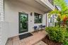 Stucco exterior entryway featuring a brick paver patio, full-light glass door, and a wall-mounted cylinder sconce