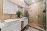 Modern dual-vanity featuring white vessel sinks, quartz countertops, wood-accent cabinetry, floor-to-ceiling vertical wood-finish wall paneling, and a