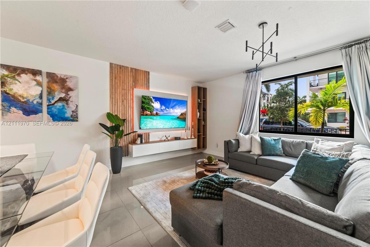 Living area featuring neutral-toned tile flooring, custom vertical wood slat accent wall, minimalist floating media console with integrated cabinetry,