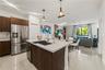 Kitchen featuring a central island with a quartz countertop, stainless steel refrigerator, dark wood-finish cabinetry, polished tile flooring, and dec