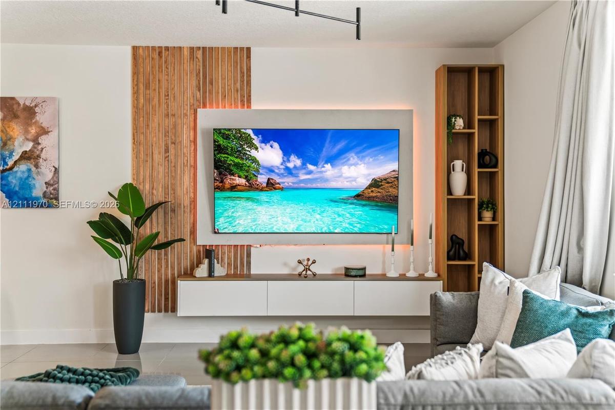 Custom media wall featuring vertical wood slat paneling, a recessed back-lit mount, a built-in floating console, and integrated full-height shelving