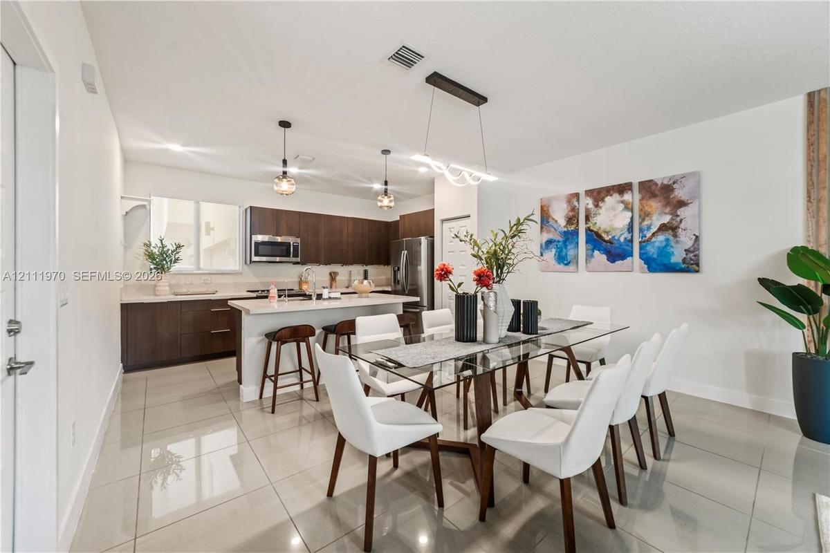 Kitchen featuring dark wood-finish cabinetry, solid-surface countertops, recessed lighting, pendant light fixtures, and large-format tile flooring