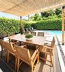 Covered patio featuring a woven reed pergola, concrete paver decking, stone aggregate inlay, and a rectangular swimming pool surrounded by a manicured