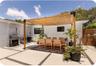 Outdoor patio featuring a custom wood-post pergola with a woven shade canopy, large-format concrete pavers with crushed stone borders, and horizontal 