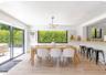Dining area featuring wood-finish flooring, a contemporary multi-arm chandelier, large sliding glass doors, and a built-in breakfast bar