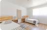 Neutral-toned interior space featuring wood-finish flooring, white walls, and a large window with natural light