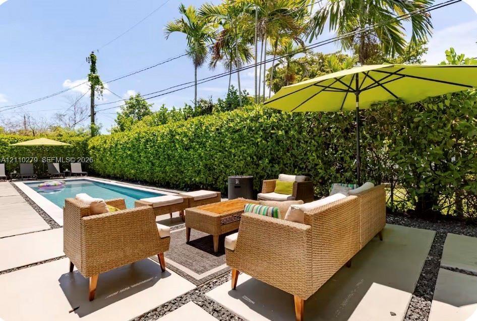 Outdoor swimming pool surrounded by concrete paver hardscaping and mature privacy hedges