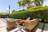 Outdoor swimming pool surrounded by concrete paver hardscaping and mature privacy hedges