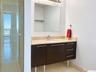 Floating vanity with dark-finish cabinetry, metal legs, stone-look countertop, and integrated sink basin, paired with a frameless mirror and a walk-in