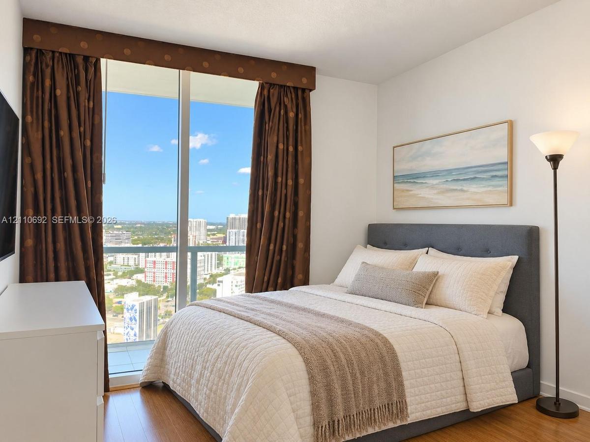 Floor-to-ceiling windows with expansive city scenery, wood-finish flooring, and a private balcony