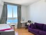 Floor-to-ceiling windows featuring expansive coastal scenery, wood-finish flooring, and a neutral color palette