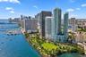 Aerial perspective of high-rise towers featuring glass-paneled facades, waterfront positioning, and proximity to an expansive green space and marina