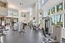 Fitness center featuring double-height ceilings, floor-to-ceiling windows, recessed lighting, and industrial-grade rubber flooring