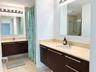 Dual floating vanities featuring dark wood-finish cabinetry, light-toned stone countertops, undermount sinks, and polished hardware, complemented by f