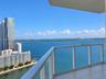 Private balcony featuring glass panel railings and tile flooring, offering expansive water and cityscape scenery