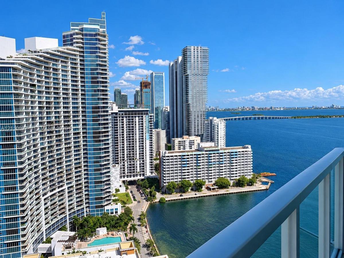 Private balcony featuring a glass and metal railing, overlooking the coastal skyline and harbor