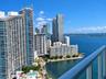 Private balcony featuring a glass and metal railing, overlooking the coastal skyline and harbor