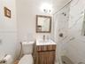 Bathroom featuring a wood-finish vanity with a rectangular sink, wall-mounted metallic lighting fixture, and shower enclosure with floor-to-ceiling st