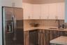 Kitchen featuring white upper cabinetry, wood-finish lower cabinetry, stone-surface countertops, a stainless steel refrigerator and dishwasher, and a 