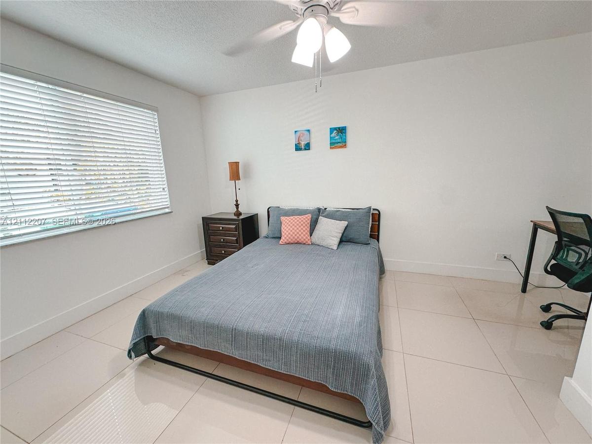 Room featuring large-format tile flooring, a multi-blade ceiling fan with integrated light fixture, and horizontal window blinds