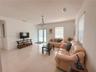 Neutral-toned tile flooring, semi-flush mount bowl lighting, and glass-paneled exterior doors with horizontal blinds